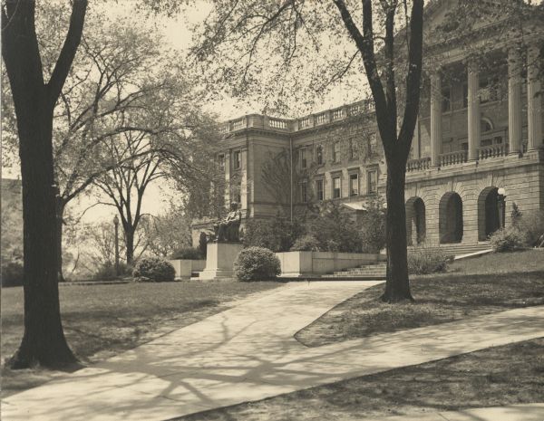 Exterior of north walkway of Bascom Hall (formerly Main Hall) on the University of Wisconsin-Madison campus. The trees are in flower, and the Lincoln Monument is on the lawn in front of the building.