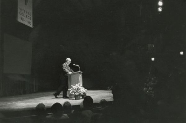 Charles Kuralt standing at a podium on the night he received the Pope John XXIII Award for Distinguished Service at Viterbo College.