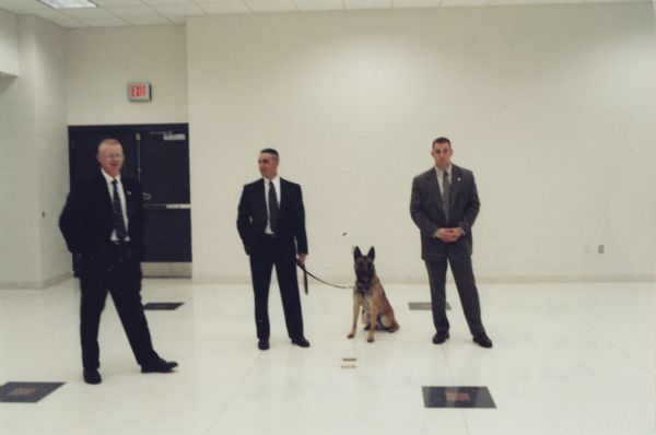 Three Secret Service agents with a guard dog at George W. Bush rally.