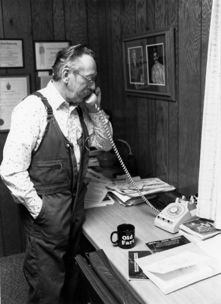 J.A. "Doc" Hines, veterinarian and politician, on the phone at his office. Wording on cup reads: "Old Fart."