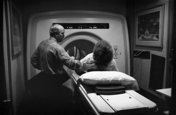 MRI technician guides patient into the machine.