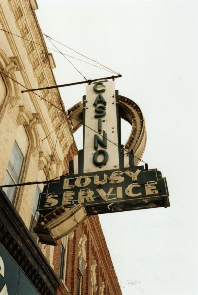 A sign on the exterior of a building reads: "CASINO - LOUSY SERVICE."