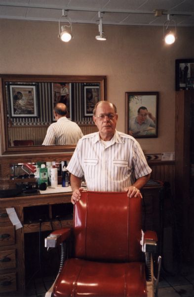 Portrait of male barber, Ken Garves, posing behind his barber chair.