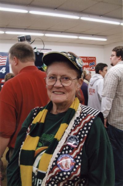 A woman wearing Green Pay Packers apparel, American flag vest, and Bush-Cheney buttons.