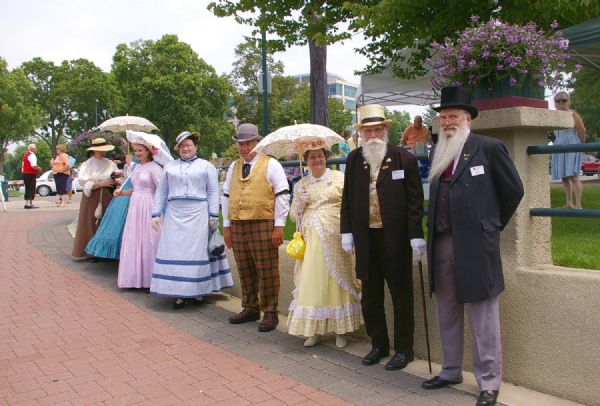 Historical reenactors in costume await visitors outside the "American Queen" steamboat.