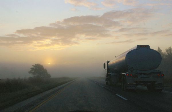 View down highway as a truck is driving towards a foggy horizon as the sun is rising. The photographer was on his way to Madison when this picture was taken.