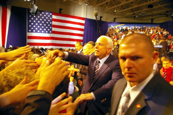 Presidential candidate John McCain greets supporters at rally. An American flag is in the background.