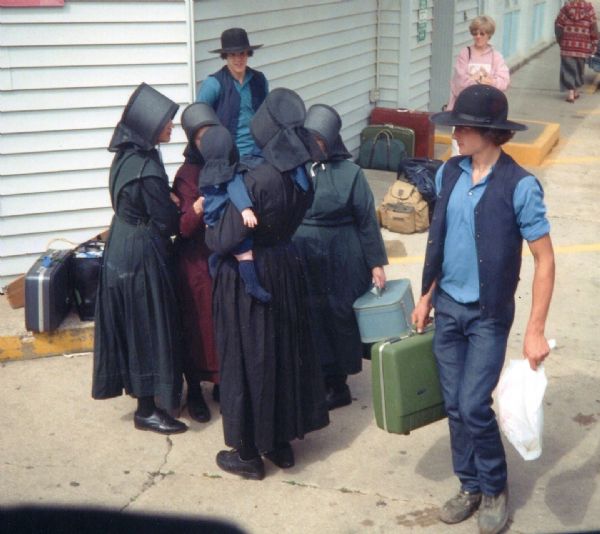 Elevated view of a group of Amish gathered together outside a bus terminal.