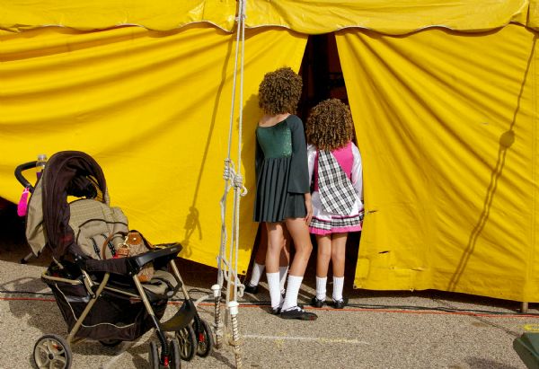 Two young girls, with hair curls, look into tent at Irishfest.