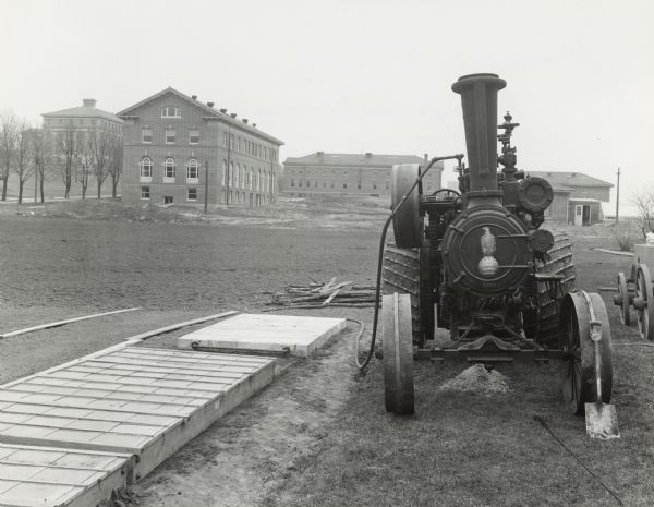 The Civil War eagle Old Abe became the trademark of the J.I. Case Company, manufacturers of steam tractors and other farm machinery. This tractor is at work for the Horticulture Department of the University of Wisconsin by preparing a seed bed by sterilizing the ground with steam. University of Wisconsin buildings are in the background.