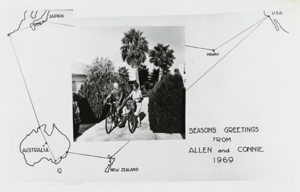 Photographic holiday postcard of a couple on their bikes in a driveway. Shrubs and palm trees surround them. A map of the Pacific Ocean is in the background. with the route of their vacation trip indicated on it. The text reads: "Seasons Greetings From Allen and Connie, 1969."