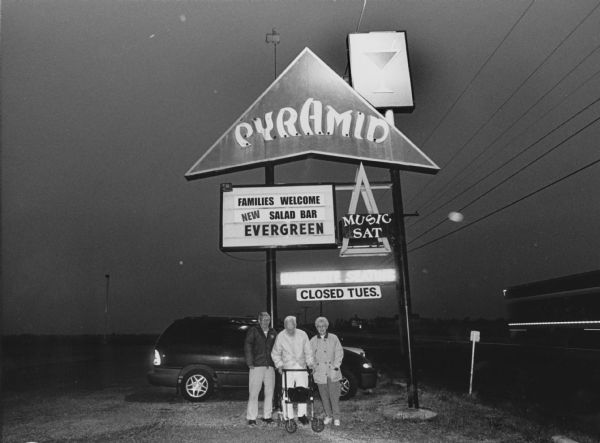 "The pyramid Supper Club is on Hwy 33, east of Beaver Dam, WI." From left to right; Ralph "Buddy" Ruecker, Ralph Widmer, and Shirley Widmer. View at night.