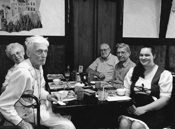 "Our waitress Adriane, in her German Dress, is our waitress at Feil's Supper Club." Seated from left to right, Ralph Widmer, Shirley Widmer, John Bodden, Ralph "Buddy" Ruecker, and Adriane, the waitress.