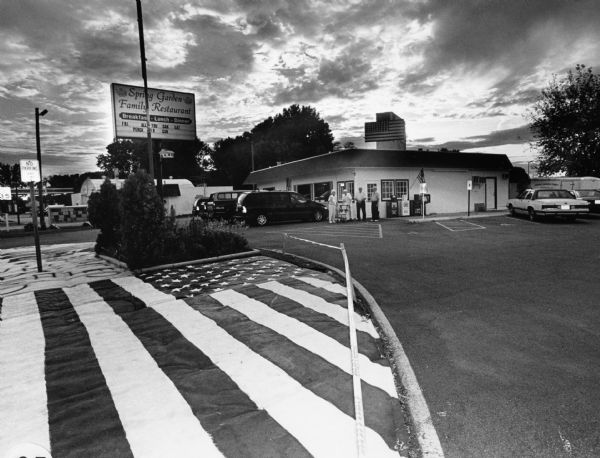 "Today we visit the Spring Garden Restaurant at 1102 Madison St, Beaver Dam." The sign in front reads, "Friday all-you-can-eat perch or cod." This photograph was taken 2 days after the one-year anniversary of the 9/11 attacks, and flags are displayed near the parking lot.