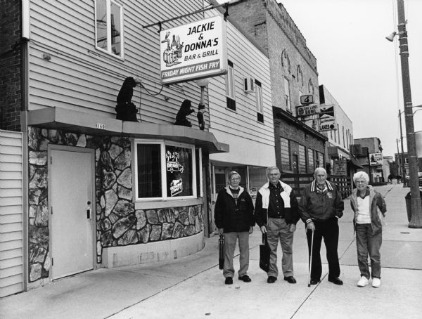 "Today we visit Jackie and Donna's Bar and Grill at 160 East Oak Street, Juneau." From left to right; Ralph "Buddy" Ruecker, Carl Bernhard, John Bodden, and Shirley Widmer.

