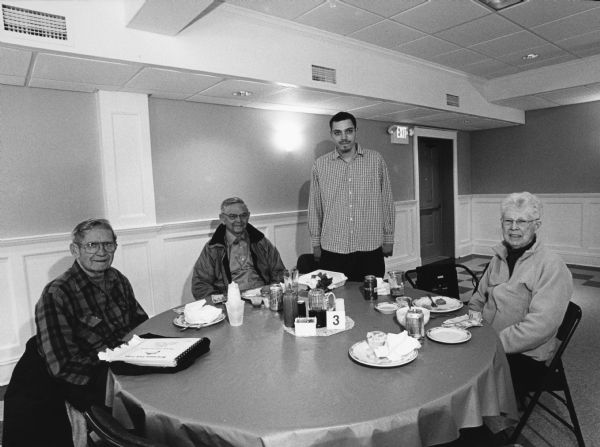 "Nick was our waiter at the American Legion in Horicon." From left to right; Ralph "Buddy" Ruecker, Carl Bernhard, Nick, and Shirley Widmer. An album of the fish fry series is sitting on the table.