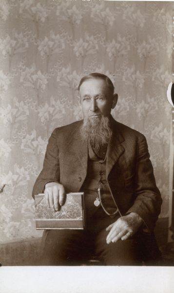 A seated portrait of Aaron Middleton, who is holding a book. Middleton was the father of William Middleton and father-in-law of Clara Middleton.