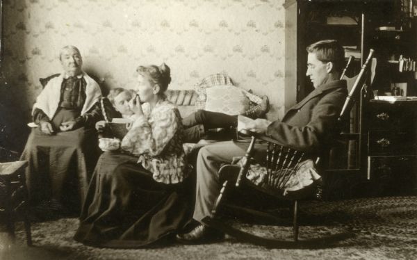 Forest Middleton sleeps on a settee as his father, William, reads and his mother and Grandmother Joanna Middleton sit nearby.