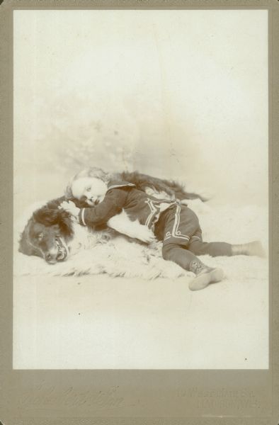 Carte-de-visite of Forest Middleton, wearing a sailor suit. He is posed resting his head on a large dog. Both are lying on a fur rug.