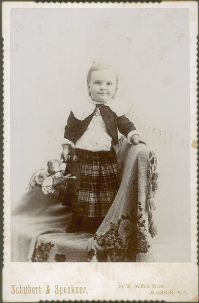 Forest Middleton poses for his portrait in a kilt, holding a toy horse. He is standing on a chair which is draped with a cloth.