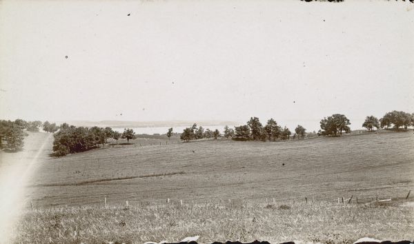 View downhill through pastures towards the northwest looking across Lake Mendota's University Bay with Picnic Point in the background.