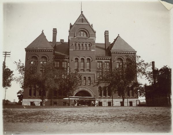 Exterior view of the Dane County Courthouse, the second on that site at 207 West Main Street. A streetcar is in front of the arched entrance. The building was erected in 1885 and razed in 1958.