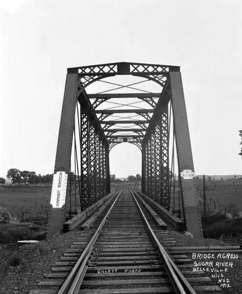 View across a railroad bridge with metal truss system over the Sugar River.