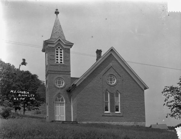 Exterior of church on hill with arched French doors and a steeple.