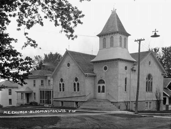 View of the church from across the intersection. The church building features a french door with a fanlight, arched windows, and a steeple.