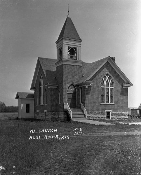 Exterior view of church. The building features arched windows and a steeple with bell.
