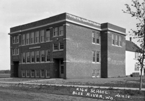 Exterior of high school. The sign on the building reads, school - 1911.