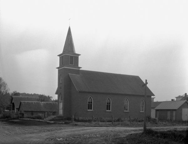 Exterior of a church. The building features a steeple with a cross and arched windows.