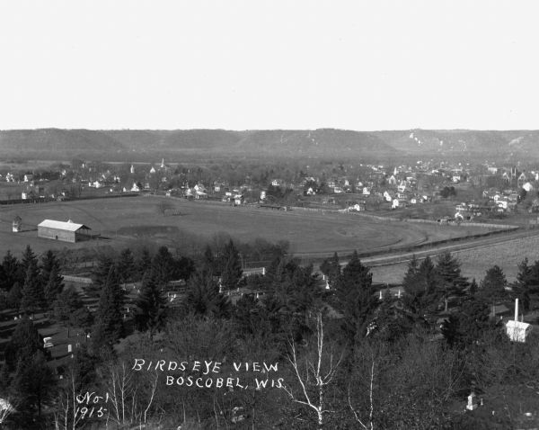 View of town. A cemetery is in the foreground and a race track is in the center.