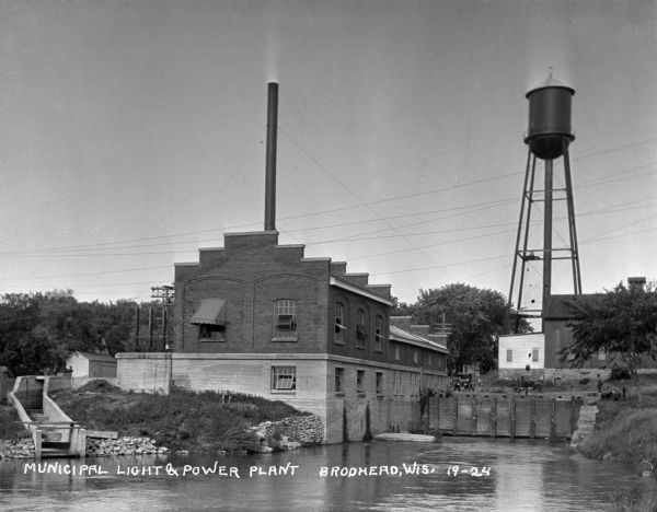 The Municipal Light and Power Plant and water tower seen from across a pond.