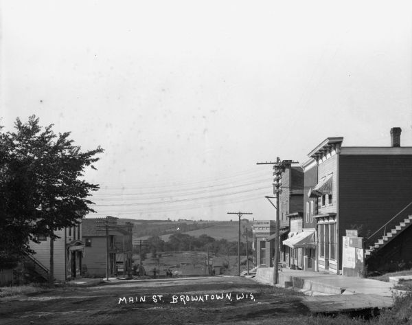 A view down Main Street. Shops are on either side of the street. Farmer's Bank is down the hill on the right.