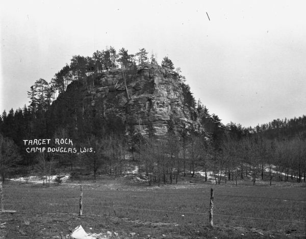 View of a large rock formation. There is a fence in the foreground.
