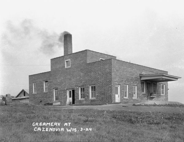 Exterior of a creamery. Smoke rises from its tall chimney.