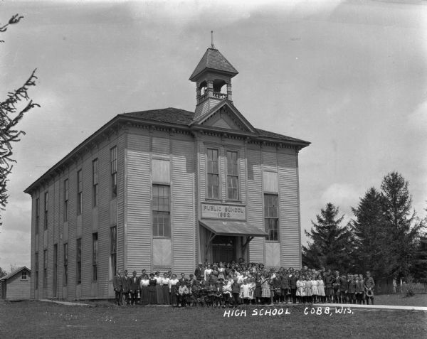 Teachers and students pose in front of the public school.