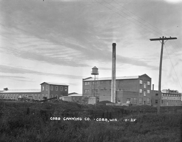 Exterior of the Cobb Canning Company. The factory features a water tower and chimney.