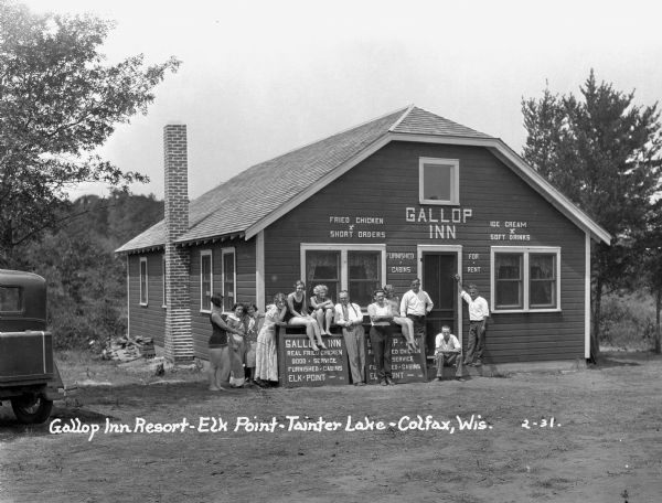 Men and women, some in bathing suits, pose in front of the Gallop Inn Resort restaurant.