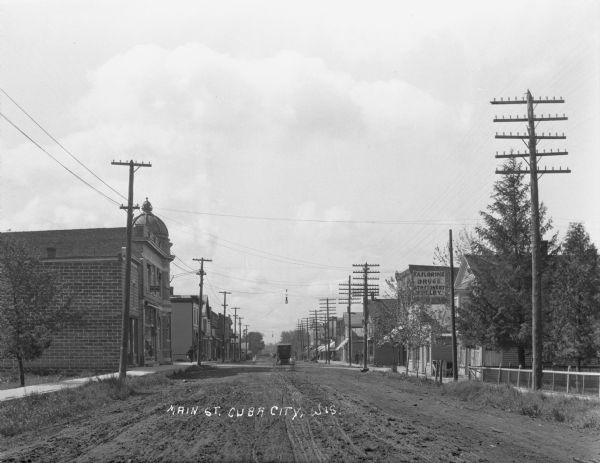 View down commercial Main Street looking south. A buggy travels down the dirt road.