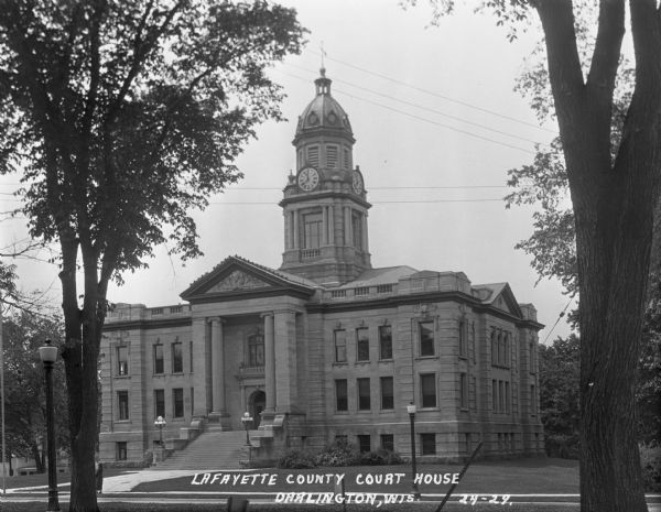 View from across road of the exterior of the Lafayette County Courthouse. The building features a Classic Revival style with a domed clock tower, columns, and limestone exterior.
