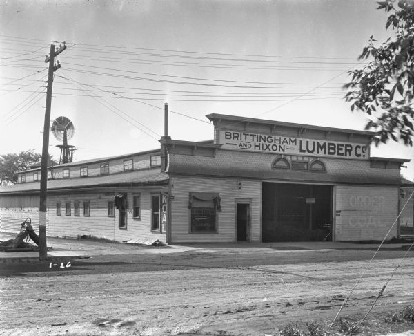 Exterior of the Company's lumber yard. A fading sign reads, "order your coal now."