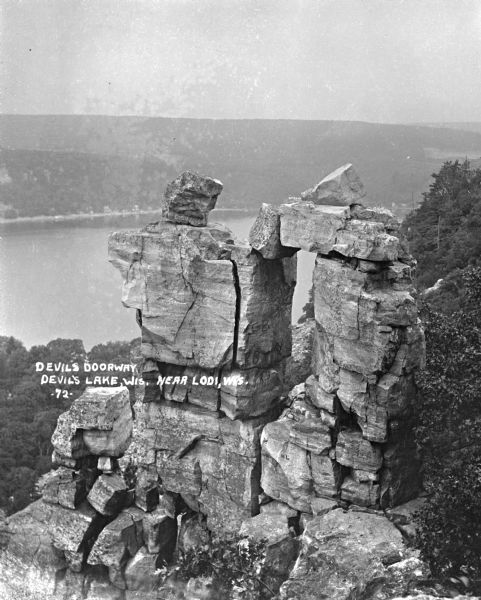 Elevated view of Devil's Doorway rock formation. Far below is Devil's Lake and the opposite shoreline with bluffs in the distance.
