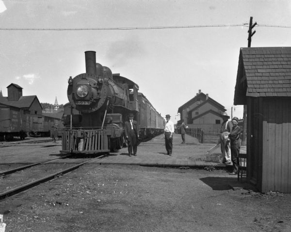 Several men pose while standing alongside a train at the Elroy depot.