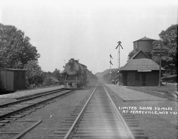 Train stopped at the Ferryville depot. The caption reads, "Limited Going 50 Miles."