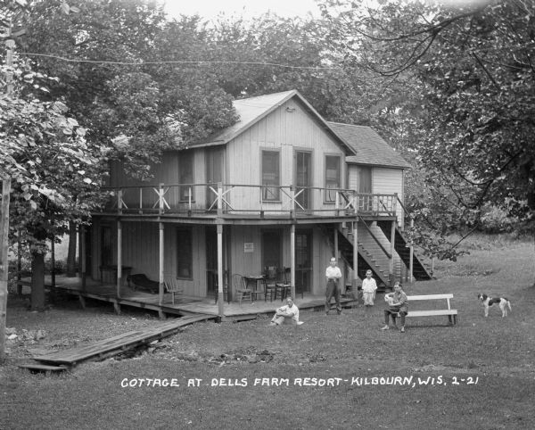 A several vacationers and their dog stand outside a two-story cabin at the Dells Farm Resort.