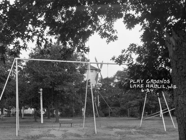 A swing set at a public park. There is a windmill in the background.