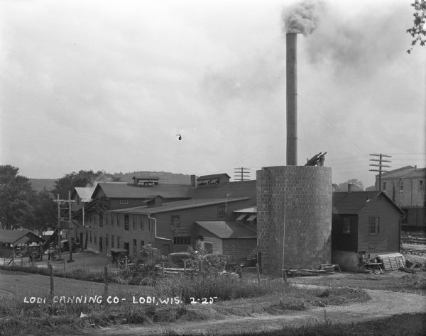 View down hill of the exterior of the Lodi Canning Company. The building features two stories and a large chimney.