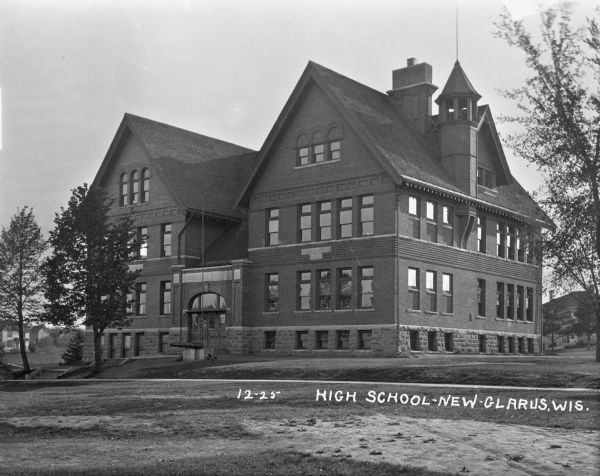 Exterior across lawn of the three-story New Glarus high school. The school building features a decommissioned Civil War cannon near the entrance.